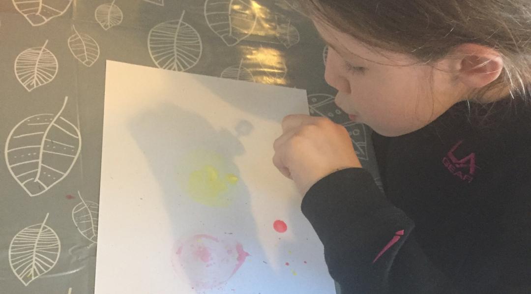 Blowing bubbles onto the paper to create process art