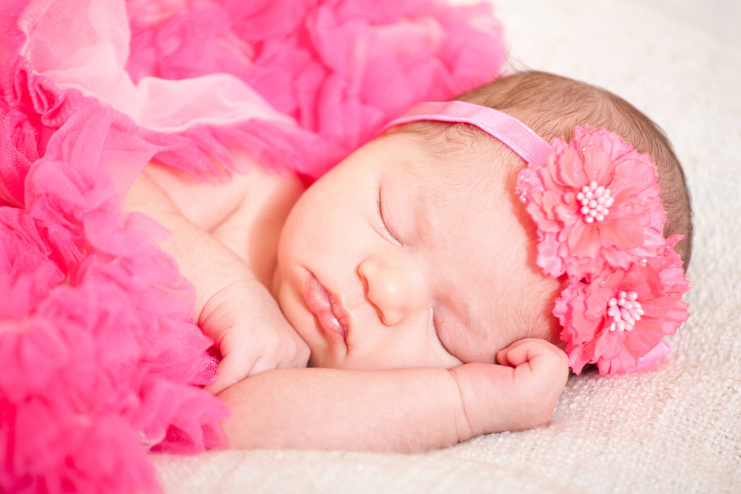 sleeping newborn baby wearing pink hairband