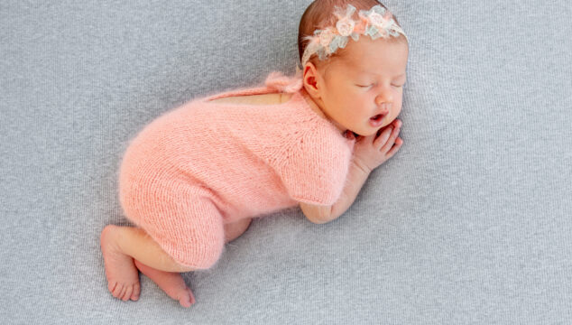 newborn baby sleeping wearing knitted peach romper