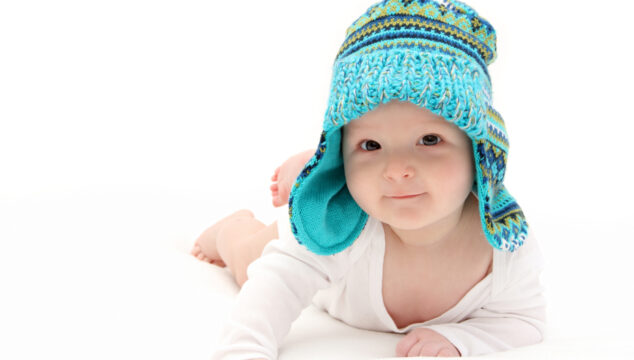 happy baby on stomach in blue knitted hat
