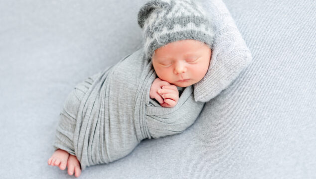 Cute newborn sleeping on tiny pillow lying on side