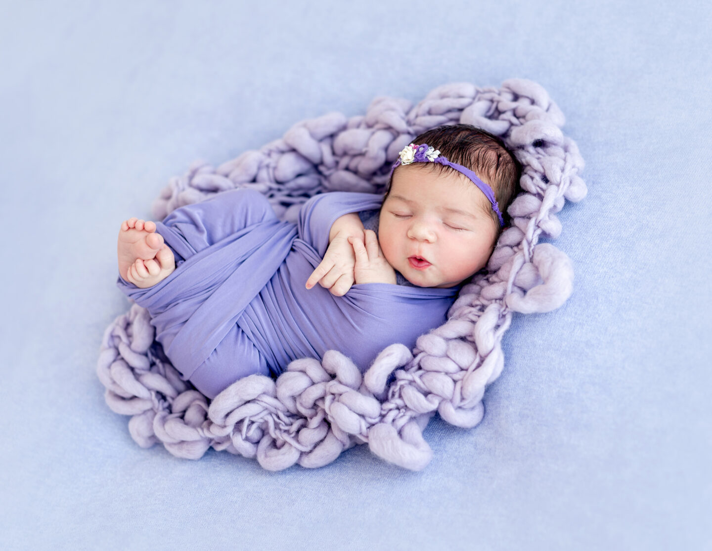 Cute newborn wrapped in purple blanked