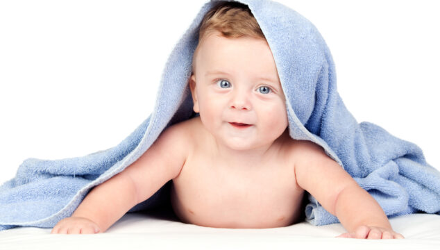 Baby with blue eyes covered by a blue towel